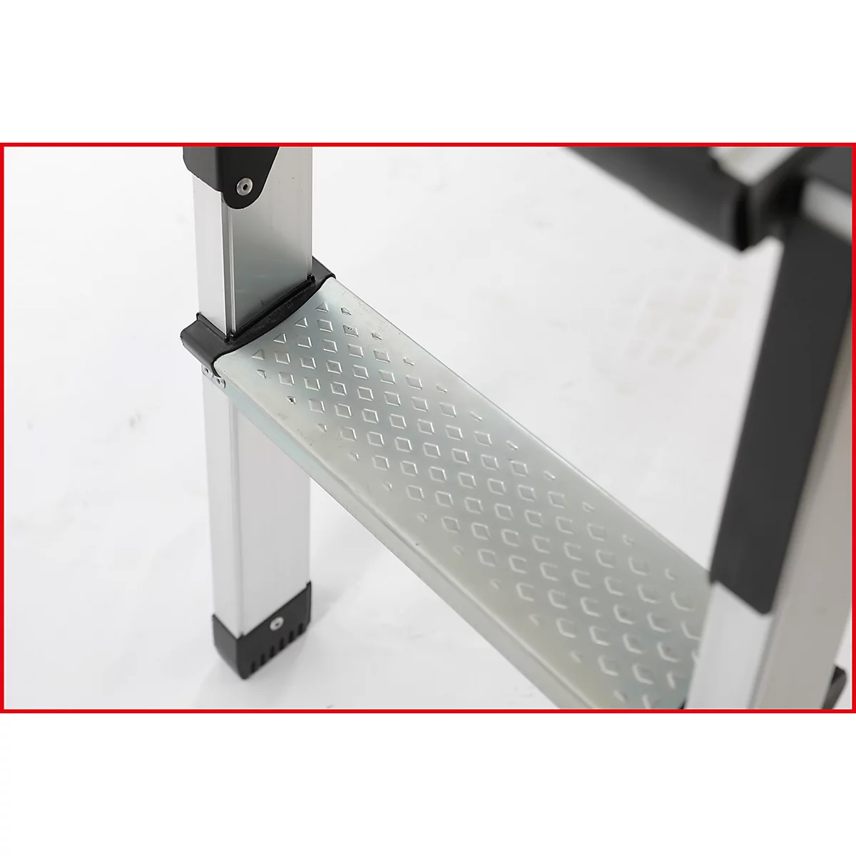 Nahaufnahme einer silbernen Trittleiter mit rutschfester Oberfläche und schwarzen Elementen.